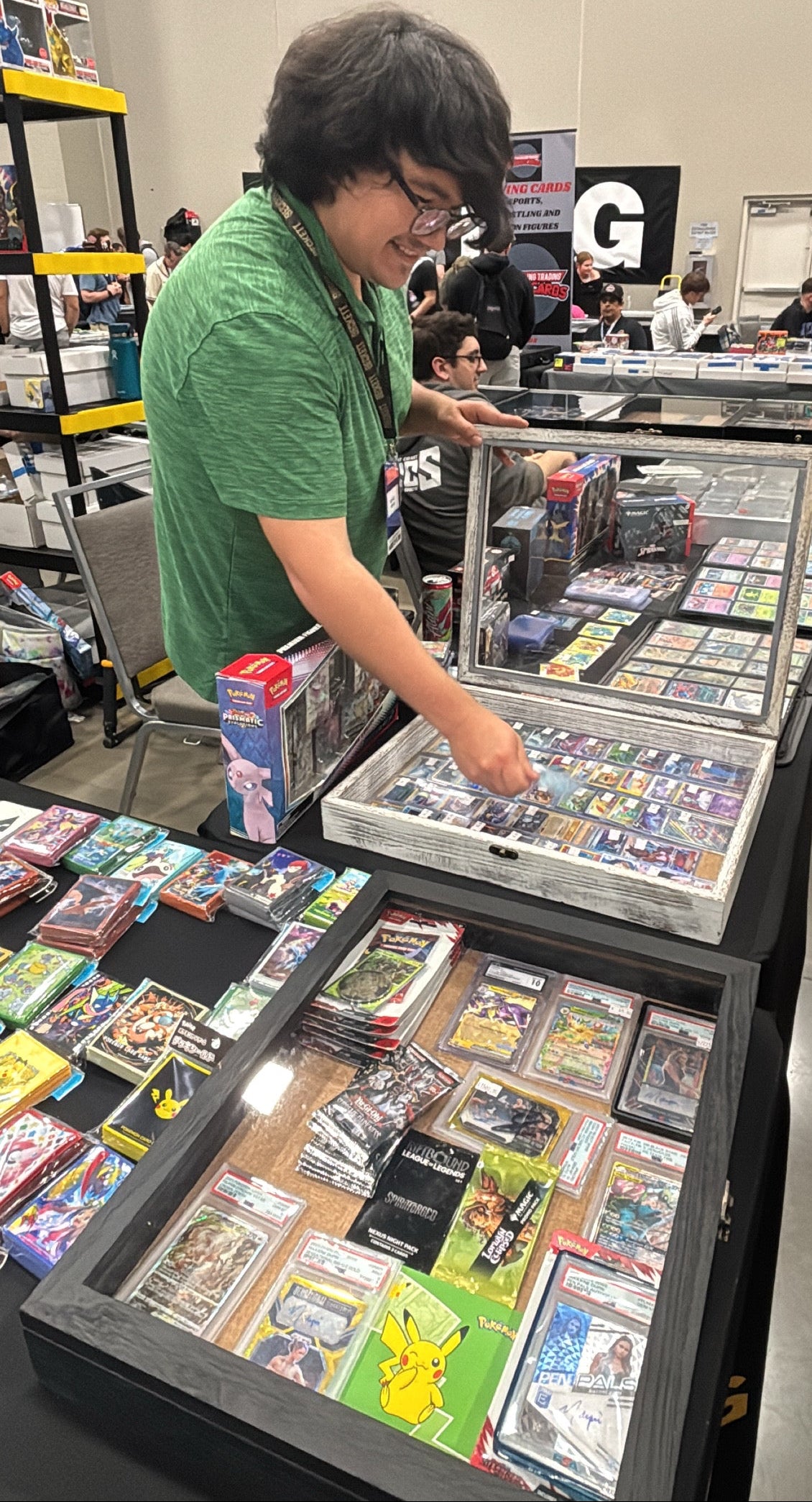 Person in a green shirt examining collectible cards at a convention.